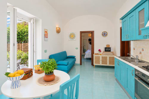 Cucina e soggiorno in tonalità azzurro turchese nell'appartamento Sant'Angelo con vista mare, elettrodomestici moderni e arredamento costiero