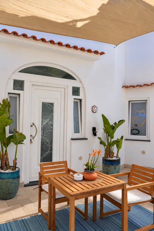 Charming patio at Chiaia di Rose B&B in Serrara Fontana, Italy, featuring wooden dining furniture, potted plants, white