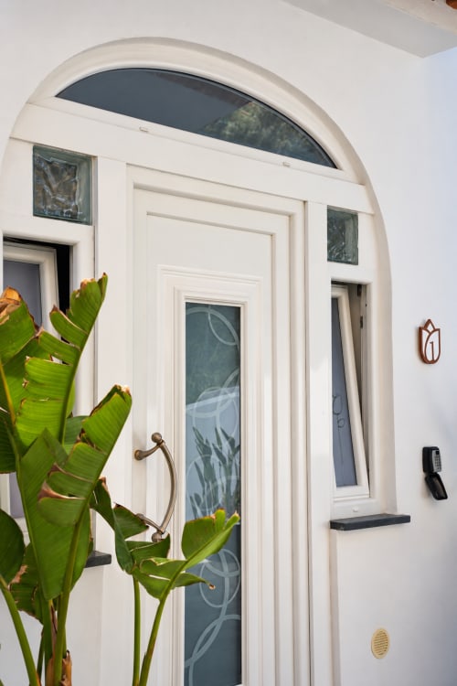 White arched entryway with dark door and transom window at Chiaia di Rose guesthouse in Serrara Fontana, Italy, decorated
