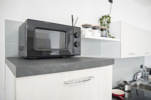 Forno a microonde retrò nero su piano grigio nella cucina moderna dell'appartamento LikeHome a Ferrara