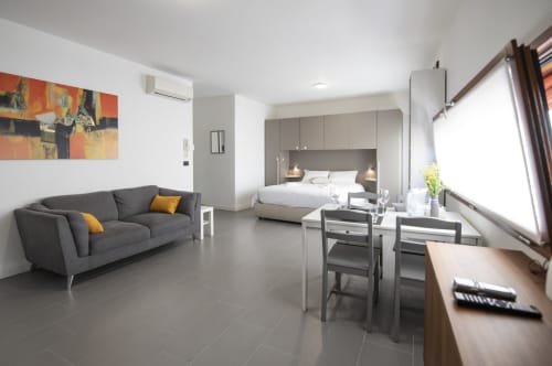 Moderno monolocale a Ferrara con divano grigio, zona living e camera con vista sulla città