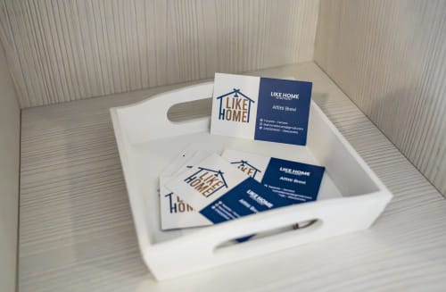Materiali di benvenuto con marchio LikeHome in vassoio bianco presso la proprietà di Ferrara, con biglietti da visita e articoli di cancelleria