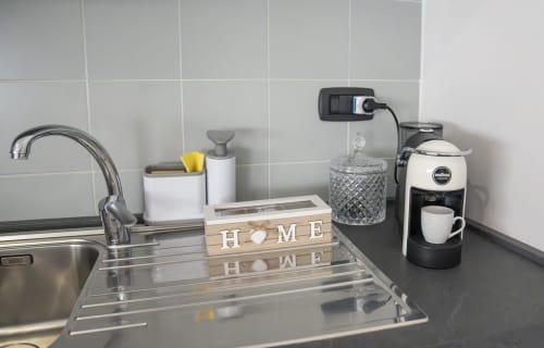 Moderno bancone cucina nell'appartamento di Ferrara con macchina caffè, lavello e insegna HOME