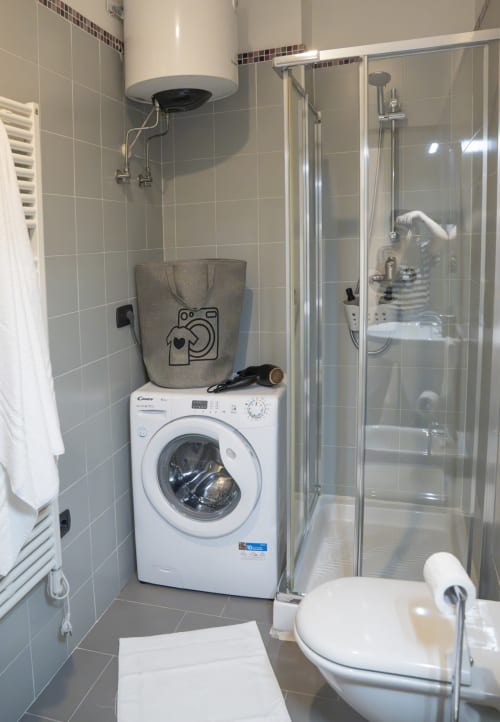 Bagno moderno con lavatrice bianca, box doccia, wc e lavabo nell'appartamento di Ferrara