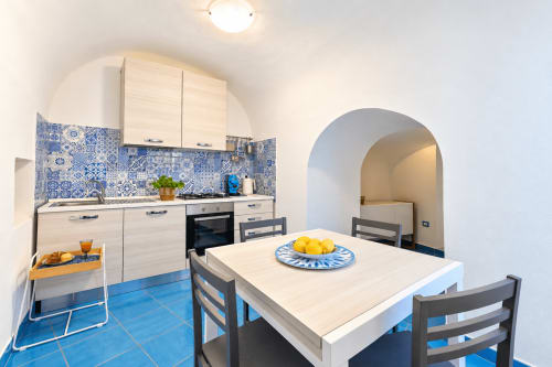 Modern blue and white kitchen with dining table at Chiaia di Rose, Serrara Fontana BnB, featuring patterned backsplash and