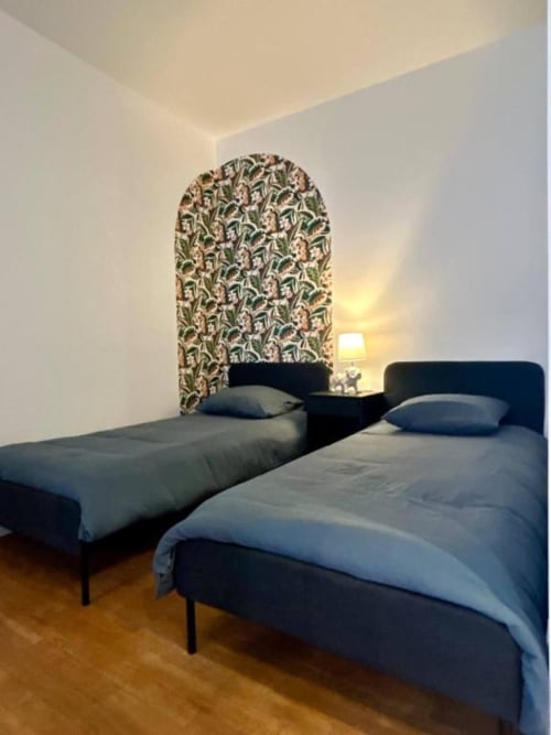 Zweibettzimmer mit blauen Betten und dekorativem Blüten-Kopfteil im Vindihouses B&B in Epinac