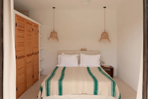 Chambre douillette au Domaine Belhazar à Essaouira avec literie rayée, luminaires suspendus tissés et volets en bois