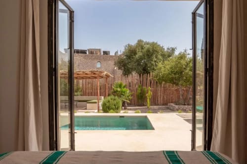 Vue ouverte sur la piscine du Domaine Belhazar, la terrasse et le fort en pierre traditionnel d'Essaouira
