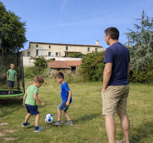 Adultes et enfants jouant au football dans le jardin herbeux du gîte Le Petit Moulin, Pouzauges