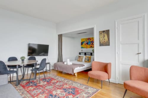 Chambre élégante à la Résidence Aurmat, hôtel boutique de Boulogne, avec lit, bureau, TV et fauteuils corail