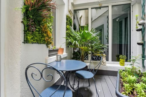 Coin salon cosy dans la cour de l'hôtel boutique Résidence Aurmat à Boulogne avec plantes en pot et chaises de bistrot bleues