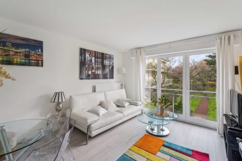 Salon lumineux et moderne à la résidence-boutique Aurmat à Boulogne-Billancourt avec canapé blanc, table basse en verre