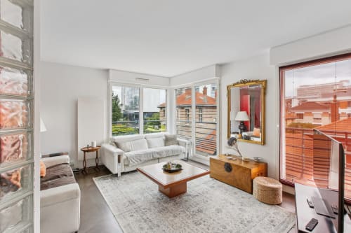 Suite moderne à la Résidence Aurmat avec canapé blanc, mobilier bois et vue sur Paris