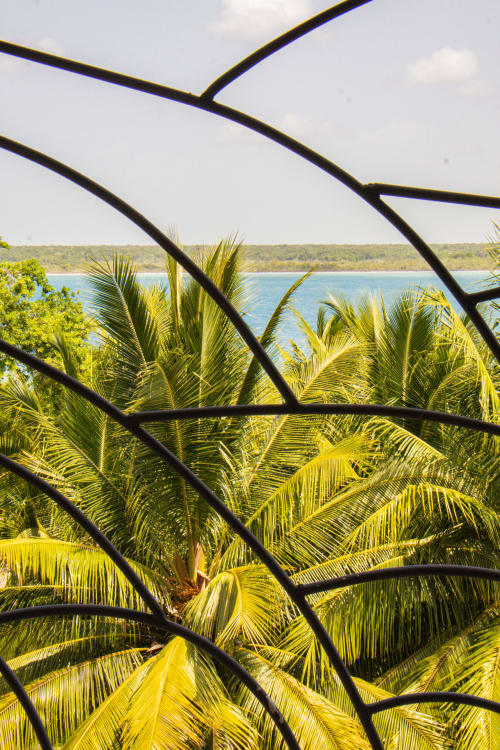 Vista del lago desde la terraza de la habitación Cayuco Maya en Bacalar, entre frondas de palma y barandales de madera oscura