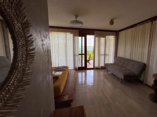 Habitación espaciosa con vista al lago en el hostal Cayuco Maya de Bacalar, con muebles, acceso a terraza y comodidades modernas
