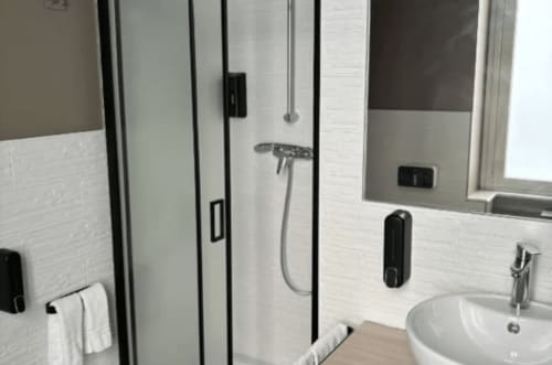 Modern bathroom at Moon Rooms By Celeste in Catania with glass shower, white tile walls, and contemporary fixtures