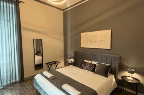 Modern bedroom at Moon Rooms By Celeste in Catania with gray headboard, neutral bedding, and contemporary decor