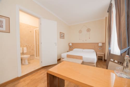 Spaziosa camera d'albergo al Green Hotel Poggio Regillo con letto matrimoniale, mobili in legno, bagno privato e vista sul giardino