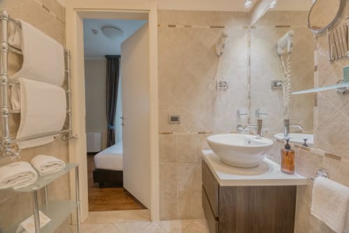 Lussuoso bagno nella Junior Suite Green Hotel Poggio Regillo, Frascati: eleganti piastrelle beige, doppio lavabo e doccia.