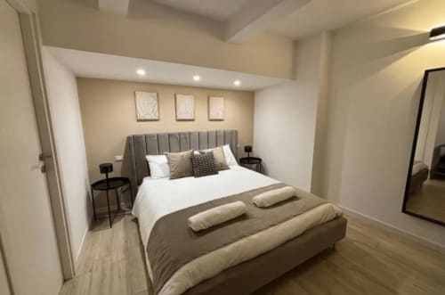 Camera moderna di Moon Rooms By Celeste a Catania con letto rivestito grigio, biancheria bianca e arredamento minimalista