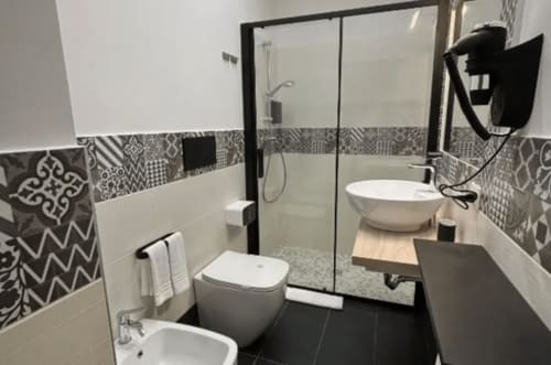 Bagno moderno presso Moon Rooms By Celeste Rooms a Catania con piastrelle a motivi bianco e nero, cabina doccia in vetro e