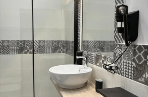 Bagno moderno delle Moon Rooms By Celeste a Catania con lavabo rotondo bianco, piastrelle grigie decorate e box doccia in vetro