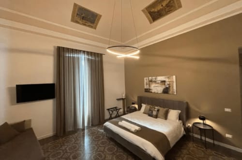 Camera moderna a Moon Rooms By Celeste a Catania con letto king, TV a parete, luci sospese e arredamento contemporaneo