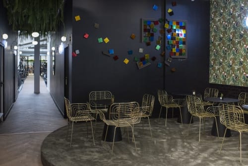 Modern lobby lounge at Résidence Aurmat boutique hotel with gold geometric chairs and colorful art installation on dark walls