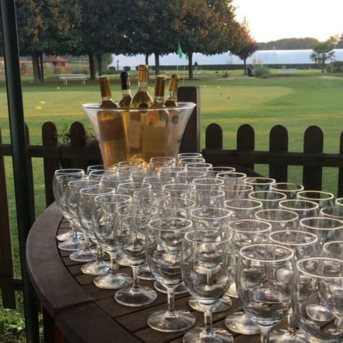 Wine glasses and bottles arranged on a terrace overlooking a green lawn at Résidence Aurmat, Boulogne-Billancourt Paris.