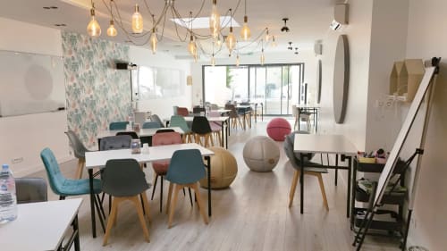 Modern hotel workspace at Résidence Aurmat Boulogne with colorful chairs, exercise balls, pendant lights, and bright natural