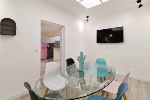 Modern lounge at Résidence Aurmat Boutique Hôtel Paris Boulogne with glass dining table, colorful chairs, and wall-mounted TV