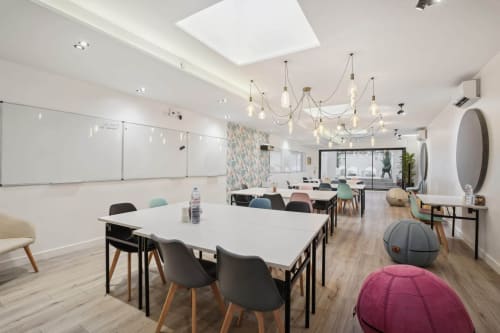 Modern meeting room at Résidence Aurmat Paris Boulogne with white tables, colorful chairs, and pendant lighting