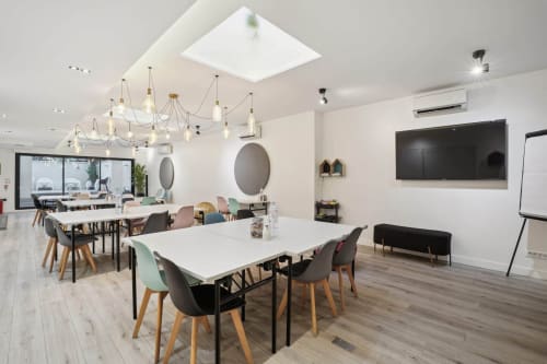 Modern meeting space at Résidence Aurmat Boutique Hôtel Paris Boulogne with white tables, colorful chairs, and elegant