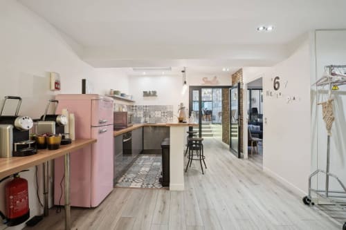 Modern boutique hotel kitchen at Résidence Aurmat Paris with pink retro fridge, wooden countertops, and open-plan living