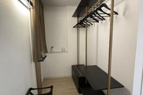 Modern walk-in closet with wooden floor, clothing rack, and black hangers at Moon Rooms By Celeste, Catania