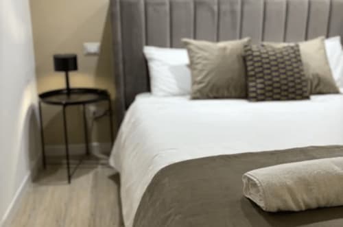 Modern bedroom at Moon Rooms By Celeste in Catania with queen bed, grey headboard, patterned pillows, and minimalist bedside