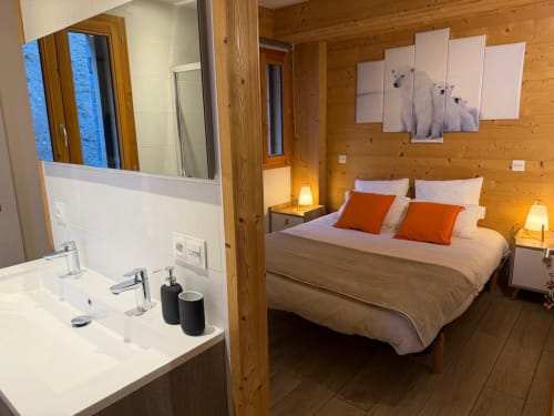 Suite chambre moderne aux Chalets d'Aline, La Plagne, avec salle de bain attenante, intérieur boisé et accents orange