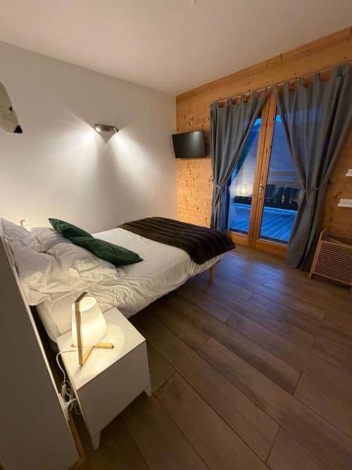 Chambre moderne aux Chalets d'Aline à La Plagne avec lit, vue sur balcon et éléments en bois