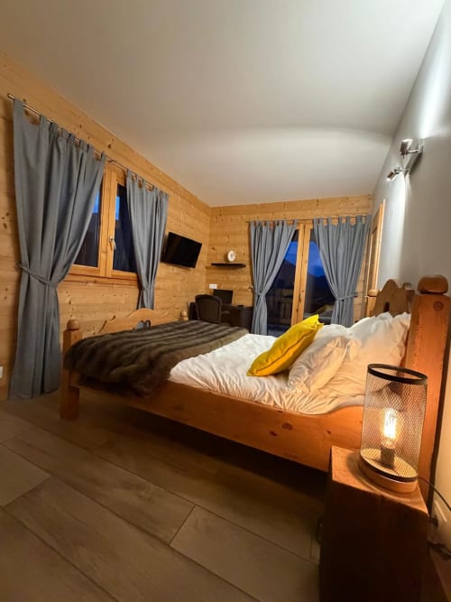 Chambre cosy du chalet en bois aux Chalets d'Aline à La Plagne avec lit, rideaux gris et vue sur les montagnes