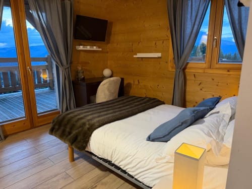 Chambre cosy en bois aux Chalets d'Aline avec vue sur le lac, lit, bureau et paysage montagnard à La Plagne.