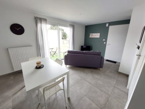 Modern open-plan apartment at Résidence des Sables, Mably, with dining table, purple sofa, and glass doors opening to terrace