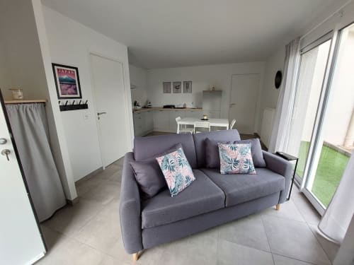 Modern apartment living room with purple sofa, kitchenette, and terrace access at Résidence des Sables in Mably