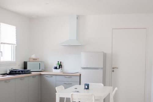 Modern kitchen dining area in Résidence des Sables apartment with white appliances, dining table, and natural light