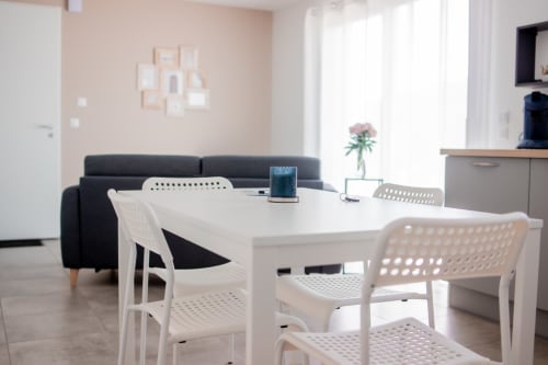 Modern dining area with white chairs at table, black sofa, kitchen, Résidence des Sables apartment, Mably