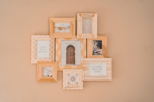 Wall gallery of wooden frames with decorative patterns and motivational text at Résidence des Sables in Mably, France