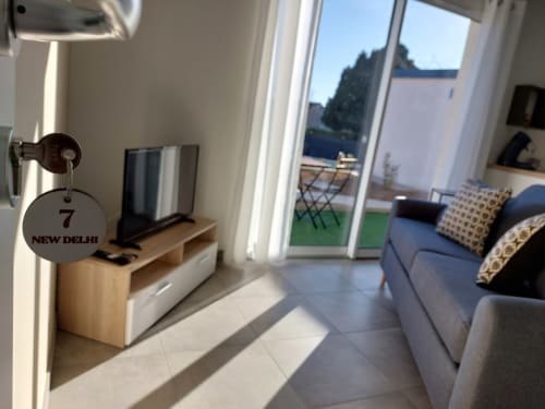 Bright apartment living room at Résidence des Sables with sofa, terrace access, and pool view in Mably, France
