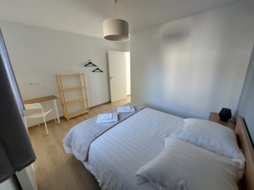 Modern bedroom at Résidence des Sables in Mably, France with bed, wooden shelf, desk and pendant light