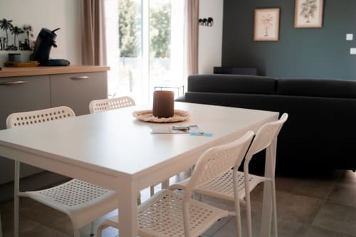 Modern dining area in Appartement 6-Nairobi at Résidence des Sables with white table, cream chairs, and black sofa