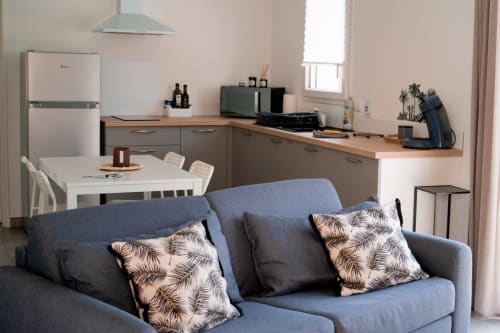 Modern studio apartment at Résidence des Sables with blue sofa, open kitchen, dining area, and amenities in Mably, France