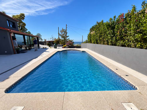 Piscina rectangular con agua azul cristalina en la casita El Román de Baiona, España, con vistas al mar